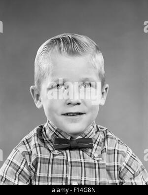 1950ER JAHRE PORTRAIT BLONDER JUNGE GLATTE HAARE TRÄGT KARIERTES HEMD BOW TIE Stockfoto