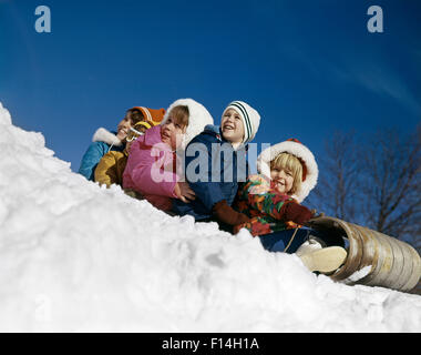 1970ER JAHREN 5 JUNGEN MÄDCHEN ZUSAMMEN WEITER RODEL LÄCHELND ZU SCHIEBEN SIE IM SCHNEE Stockfoto