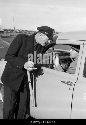 1950ER JAHREN POLIZIST MIT GESTOPPTEN AUTOFAHRER SCHREIBEN TICKET Stockfoto