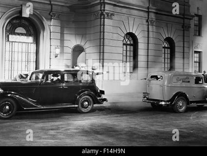 1930ER JAHREN FILM NACH WIE VOR DER NÄCHTLICHEN SCHIEßEREI ZWISCHEN GANGSTERN IN EINEM GEPARKTEN AUTO UND EIN LASTWAGEN PANEL Stockfoto