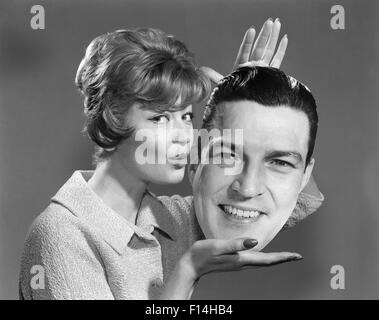 1950S 1960S FRAU MIT LEBENSGROßEN FOTO BILD VON DEN MÄNNERN DEN KOPF IN DIE HÄNDE, DIE LIPPEN ZU KÜSSEN KRÄUSELN Stockfoto