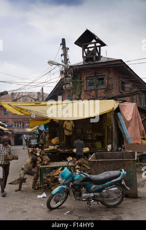 Indien, Jammu & Kaschmir, Srinagar, Hazratbal, Mann die Ernte herauf Stapel Brennholz aus stall Stockfoto