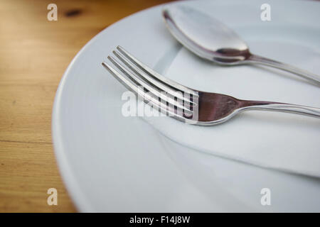 Gabel und Löffel mit weißen Teller auf Holztisch Stockfoto