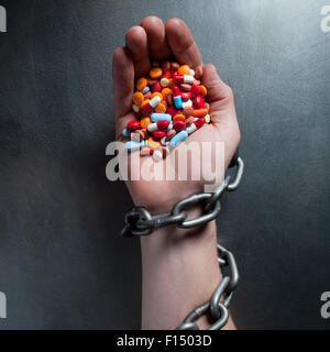 Studio hautnah von Menschenhand mit Kette halten Haufen von Arzneimitteln Stockfoto