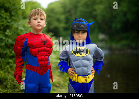 Batman und Spiderman Kinderspiele: zwei pre-Teen jungen Kindern im Grundschulalter spielen im Freien an einem Sommerabend, verkleidet als Comic-Buch-Superhelden Batman und Spiderman. UK Stockfoto