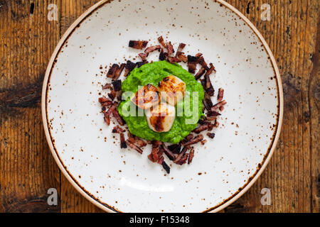 Jakobsmuscheln mit Erbsenpüree und knusprigem Speck Stockfoto