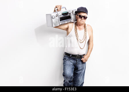 Senior woman in einem Hip-Hop-Outfit tragen Ghettoblaster über seine Schulter und schaut in die Kamera Stockfoto