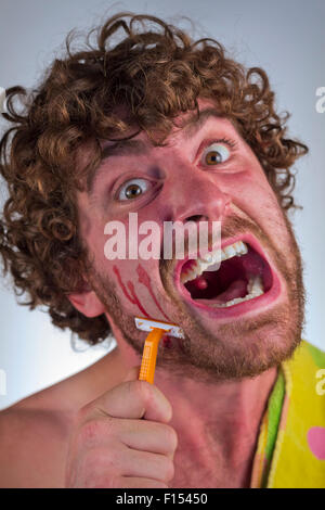 Dummer bärtiger Mann schneidet sein Gesicht beim Rasieren seinen Bart Stockfoto