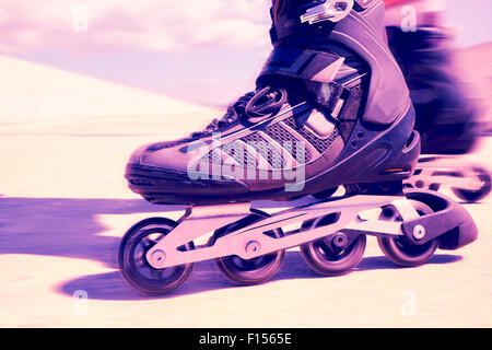 Nahaufnahme von den Füßen eines jungen Mannes Rollerskating mit Inline-Skates, mit einem Filtereffekt Stockfoto
