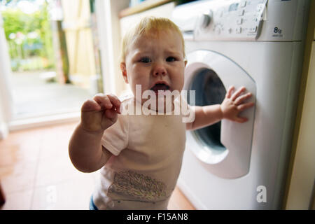 Ein Zahnen elf Monate altes Baby in der Küche ihres Hauses mit den Schmerzen und Beschwerden von Zahnschmerzen zu weinen. Stockfoto