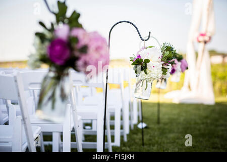 Blumen hängen am Ende von Stuhlreihen bei Hochzeit Stockfoto