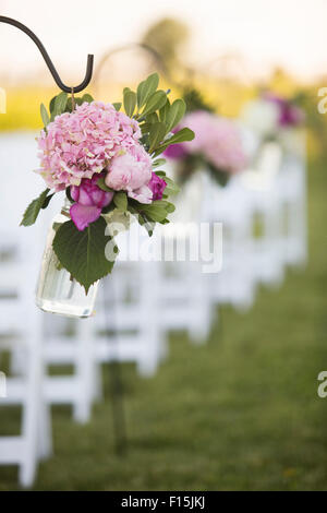 Blumen hängen am Ende von Stuhlreihen bei Hochzeit Stockfoto