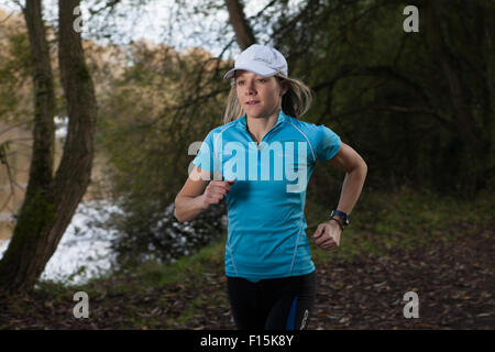 Nahaufnahme der weibliche Läufer tragen Baseball-Cap in ländlicher Umgebung in der Nähe eines Flusses. Stockfoto