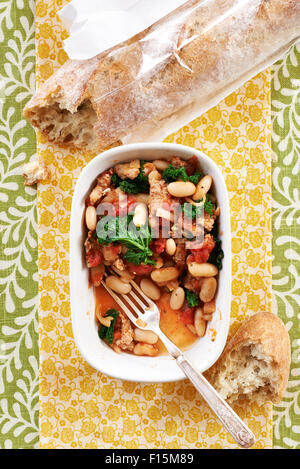 Würstchen, Bohnen und Grünkohl Eintopf mit Gabel in einer Schüssel und knusprigem Brot, Studio gedreht Stockfoto