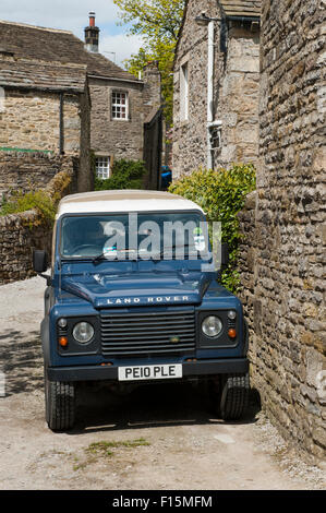 Vorderansicht des sauber, glänzend, blaue Land Rover Defender (ikonische robuste 4 x 4 Fahrzeug) geparkt auf sonnigen Yorkshire Dales Dorf Straße - Burnsall, England, UK. Stockfoto