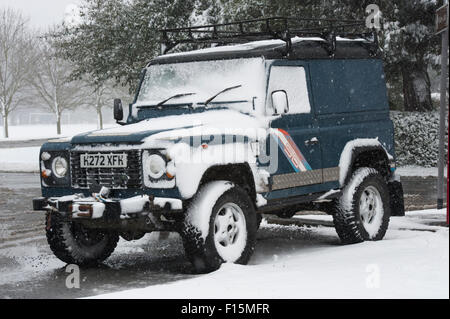 Teils überdachte blau Land Rover Defender 90 (robuste 4 x 4 Fahrzeug) im weißen Schnee geparkt am Straßenrand auf einen schneereichen Winter Tag - Ilkley, England, UK. Stockfoto