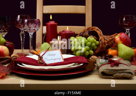 Happy Thanksgiving Tischdekoration in den klassischen rustikalen Farben auf Holztisch mit Füllhorn Herzstück, Kerzen und Obst. Stockfoto