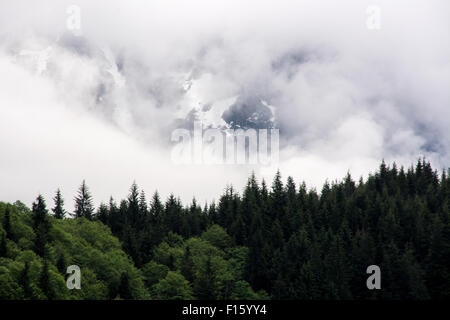 Schneebedeckte Berge, eingehüllt in Wolken und Nebel über der Great Bear Rainforest, British Columbia, Kanada. Stockfoto