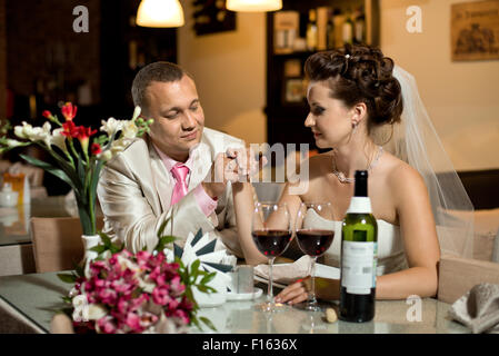 frisch verheiratetes Paar sitzt am Tisch im Restaurant, Romantik, Hochzeitsessen Stockfoto