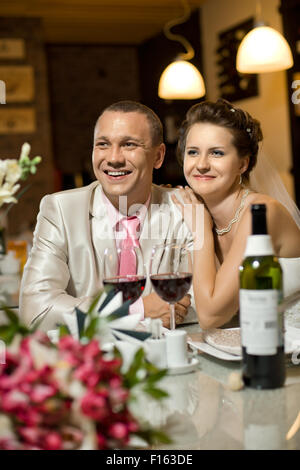 frisch verheiratetes Paar sitzt am Tisch im Restaurant, Romantik, Hochzeitsessen Stockfoto