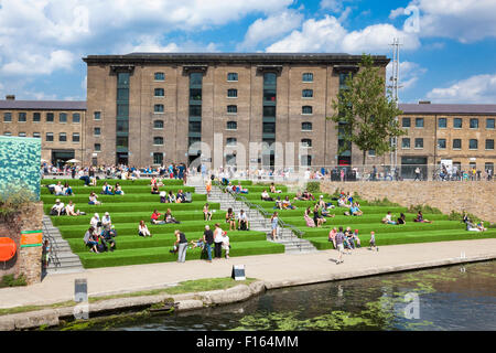 Central Saint Martins Gebäude in King's Cross und Leute sitzen am Regents Canal, London, England Stockfoto