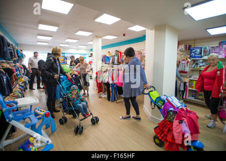 Frauen Shopper suchen Schnäppchen billig Kinder Kleidung in einen neuen Zweig der Barnardo Nächstenliebe Kindermoden Geschäft in Aberystwyth Wales UK Stockfoto