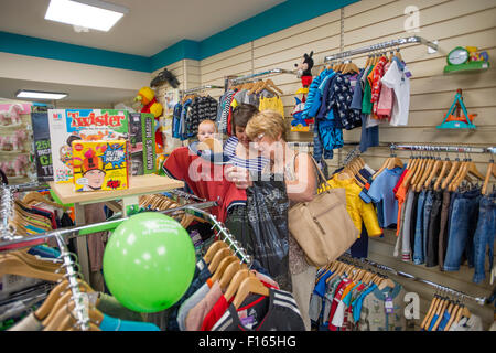 Frauen Shopper suchen Schnäppchen billig Kinder Kleidung in einen neuen Zweig der Barnardo Nächstenliebe Kindermoden Geschäft in Aberystwyth Wales UK Stockfoto