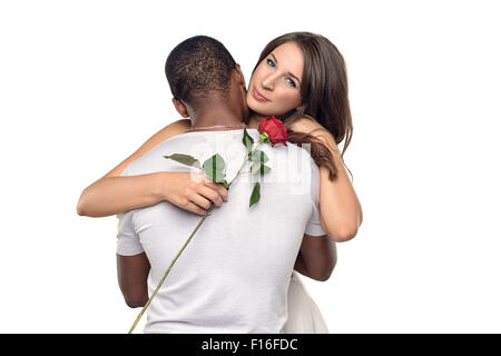 Sentimentale junge Frau umarmt ihr Freund oder geliebten, wie sie lächelt zärtlich nach unten eine einzelne rote rose er gerade h gegeben hat Stockfoto