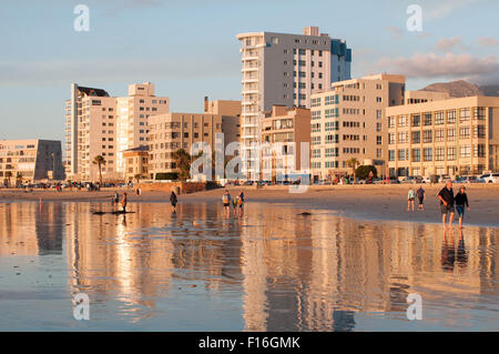 Nicht identifizierte Personen direkt am Strand bei Sonnenuntergang in The Strand in der Nähe von Kapstadt. Es ist ein Stockfoto