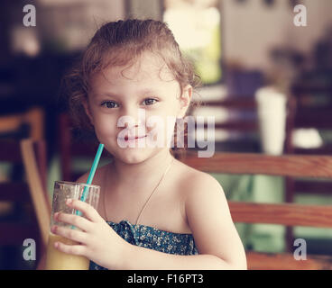 Glücklich lächelnde Kind Mädchen trinken frische Saft aus Glas im Café. Getönten Closeup portrait Stockfoto