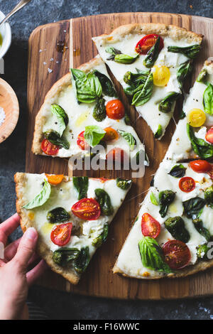 Padron Pfeffer und Cherry Tomaten Pizza, glutenfrei und Vollkornprodukte. Eine Hand, ein Stück nehmen. Stockfoto