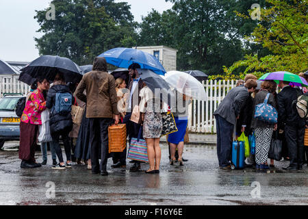 Junge Oper Fans warten im strömenden Regen bei Lewes Bahnhof einen Bus nehmen sie in Glyndebourne Opera House, Lewes, Sussex, UK Stockfoto