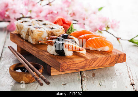 Sushi Set mit Sashimi und Sushi-Rollen auf Oliven Holz Brett auf blauem Hintergrund aus Holz Stockfoto