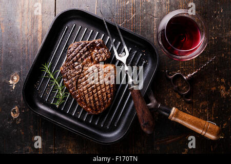 Gegrillte Black Angus Steak Ribeye auf Eisen Grillpfanne auf hölzernen Hintergrund mit Wein Stockfoto