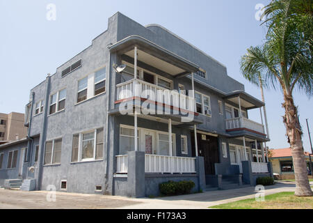 Alte Wohnung grau-blau mit weißem trim kleine Palme vor der Tür Stockfoto