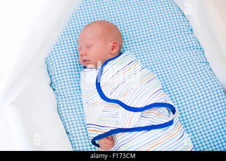 Entzückende Neugeborene schlafen gepuckte im weißen Bett. Neue geborene junge ein Nickerchen in blauen Krippe. Kinder schlafen. Windeln für Kleinkinder. Stockfoto