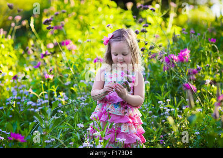 Kleines Mädchen mit Blumen im Garten zu spielen. Kinder spielen im Freien im Sommer. Kinder im Garten. Kinder Pflanzen Blume Stockfoto