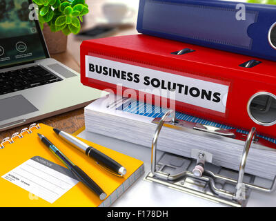 Roten Ring-Binder mit Inschrift-Business-Lösungen auf Hintergrund Tabelle mit Büromaterial, Laptop, Berichte zu arbeiten. Getönten Stockfoto