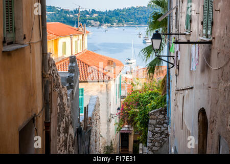 Schmale Straße mit alten Gebäuden führt zu Mittelmeer in der mittelalterlichen Stadt Villefranche-Sur-Mer an der Côte d ' Azur, Frankreich. Stockfoto