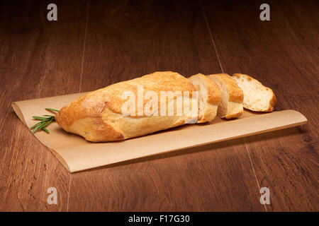 In Scheiben Ciabatta Brot und Rosmarin auf Backpapier auf dunklen Holztisch Hintergrund Stockfoto