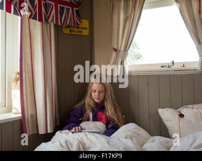 Ein Zehn Jahres altes Mädchen spielt auf einem iPad in das Bett einer Karawane. Stockfoto