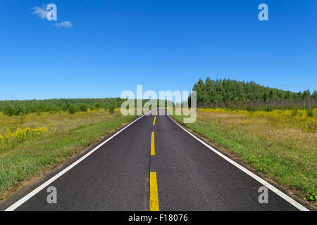 Asphalt Landstraße mit einer Zeile der gestrichelten gelben und zwei Linien von festen weißen Fahrbahnmarkierungen Stockfoto