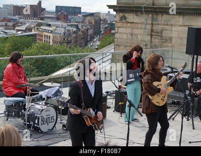 Liverpool, Vereinigtes Königreich. 29. August 2015. Sie Beatles, eine schottische Beatles Tribute Band, neu die Beatles letzten öffentlichen Auftritt auf dem Dach des Apple-Hauptquartier in 1969 durch das Spielen auf Liverpool Central Library am Samstagnachmittag, den 29. August. Es war Teil des internationalen Beatles feiern. Bildnachweis: Pak Hung Chan/Alamy Live-Nachrichten Stockfoto