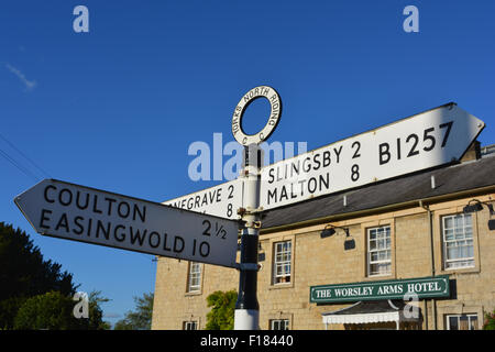 North Riding, York Wegweiser und The Worlsey Arms Hotel, Hovingham, North Yorkshire, UK Stockfoto