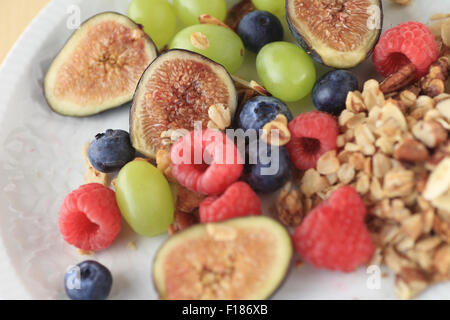 Frische Feigen, Heidelbeeren, Himbeeren und Trauben mit einer Portion Müsli Stockfoto