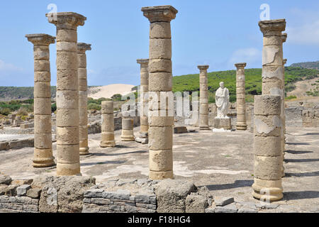 Gerichtsgebäude der römischen Bauruine Baelo Claudia mit Trajan-Statue in der Bolonia-Bucht mit Sanddüne am Strand von Bolonia am fernen Ende (Tarifa, Cádiz, Spanien) Stockfoto