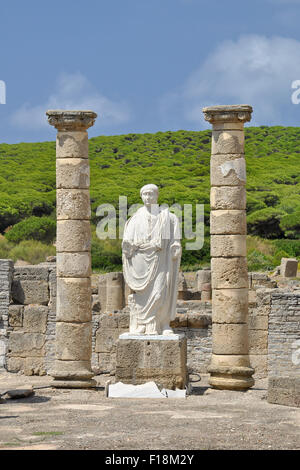 Kaiser Trajan-Statue in der Gerichtsstätte der römischen Bauruine Baelo Claudia in der Bucht von Bolonia mit Pinienwald im äußersten Ende (Tarifa, Cádiz, Andalusien, Spanien) Stockfoto