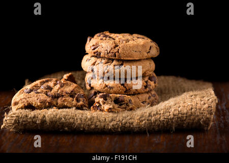 Schokoladen-Plätzchen auf weißem Leinen Serviette auf Holztisch. Schuss auf Kaffee buntem Tuch Stockfoto