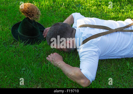 Mann in bayerischer Tracht, die draußen auf der Wiese liegen Stockfoto