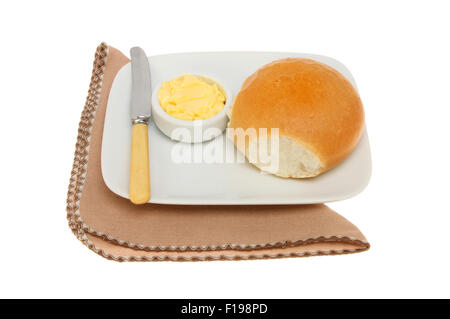 Knusprige Brötchen mit Butter und ein Messer auf einem Teller mit einer Serviette isoliert gegen weiß Stockfoto